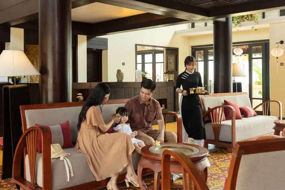 Family relaxing in the Indochine-style lobby lounge at Victoria Hoi An Beach Resort & Spa